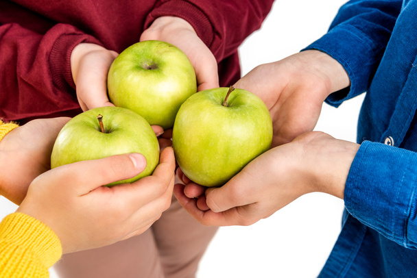 περικοπεί θέα από τα παιδιά που είναι κρατώντας πράσινα μήλα που απομονώνονται σε λευκό - Φωτογραφία, εικόνα