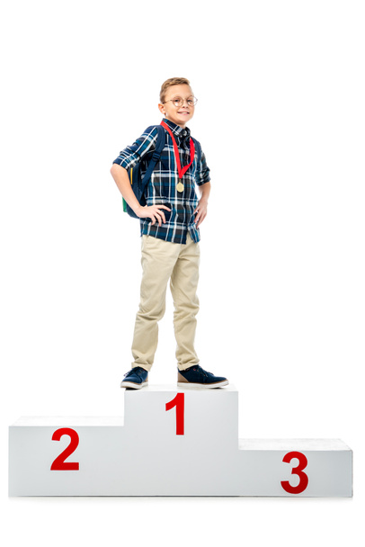 happy boy standing on winner podium, smiling and looking at camera isolated on white - Photo, Image