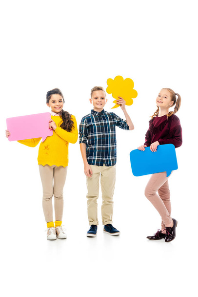happy kids smiling, holding multicolored speech bubbles and looking at camera isolated on white - Photo, Image