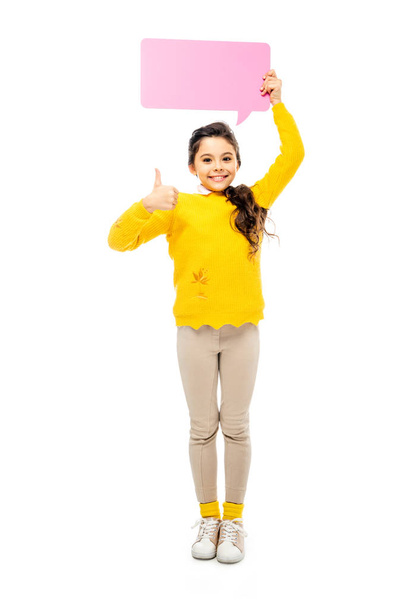 cheerful schoolgirl holding pink speech bubble over head, showing thumb up and looking at camera isolated on white - Foto, Bild