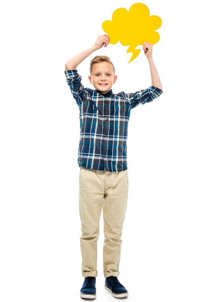niño sonriente sosteniendo burbuja de habla amarilla sobre la cabeza y mirando a la cámara aislada en blanco
 - Foto, Imagen