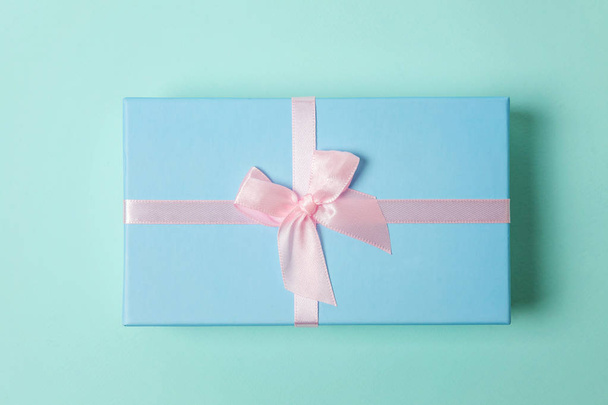Pequeña caja de regalo envuelta en papel azul aislado sobre fondo geométrico de moda colorido pastel rosa. Navidad Año Nuevo cumpleaños celebración de San Valentín presente concepto romántico
 - Foto, imagen