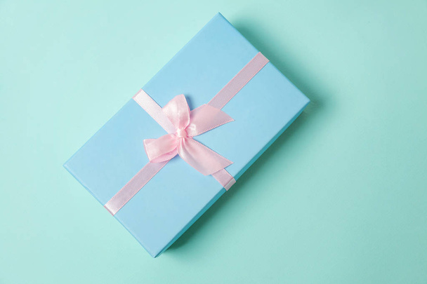 Κουτί μικρό δώρο τυλιγμένο μπλε χαρτί που απομονώνονται σε ροζ παστέλ πολύχρωμα μοντέρνα γεωμετρικό υπόβαθρο. Χριστούγεννα Πρωτοχρονιά γενέθλια ημέρα του Αγίου Βαλεντίνου γιορτή παρουσιάσει ρομαντική έννοια - Φωτογραφία, εικόνα