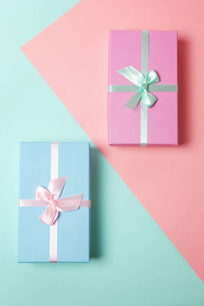Pequeña caja de regalo envuelta en papel rosa y azul aislado sobre fondo geométrico de moda colorido pastel azul y rosa. Navidad Año Nuevo cumpleaños celebración de San Valentín presente concepto romántico
 - Foto, imagen