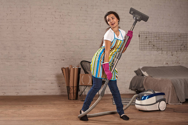 Mujer feliz limpiando casa, bailando con aspiradora y divirtiéndose, espacio para copiar
. - Foto, Imagen