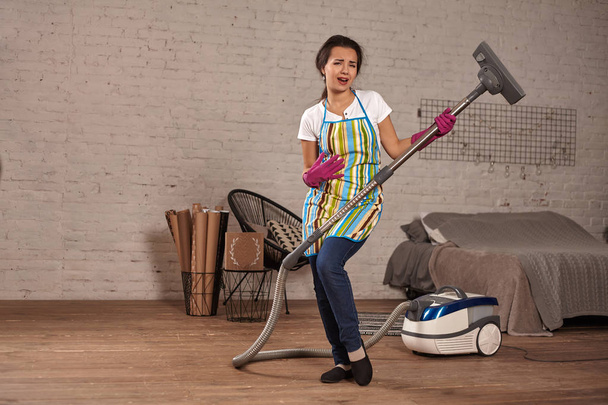 Mujer feliz limpiando casa, bailando con aspiradora y divirtiéndose, espacio para copiar
. - Foto, Imagen