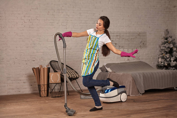 glückliche Frau, die zu Hause putzt, mit Staubsauger tanzt und Spaß hat, Raum kopiert. - Foto, Bild