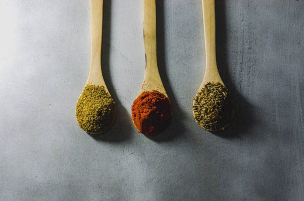 especias tpicas en tres cucharas de maderas por color comino semillas pimiento - Fotografie, Obrázek