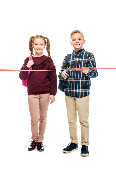 smiling pupils cutting red ribbon and looking at camera isolated on white - Photo, Image