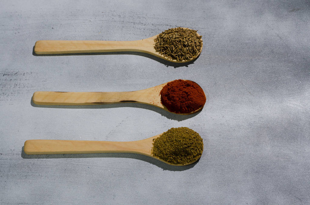 especias tpicas en tres cucharas de maderas por color comino semillas pimiento - Fotografie, Obrázek
