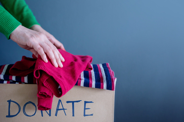 Donatie Concept. Vrouw Droping haar gebruikte oude kleding in een doos doneren - Foto, afbeelding