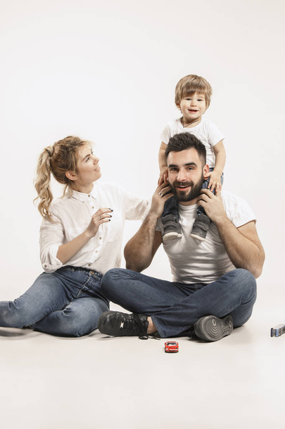 happy family with kid sitting together and smiling at camera isolated on white - Fotoğraf, Görsel