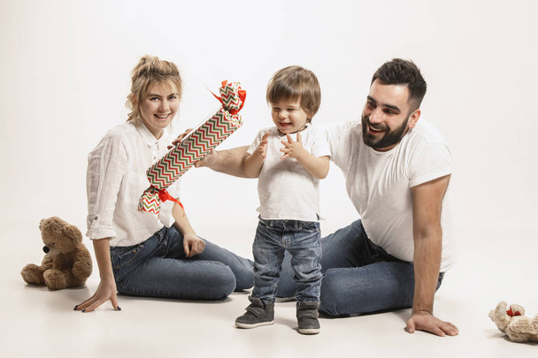happy family with kid sitting together and smiling at camera isolated on white - Фото, зображення