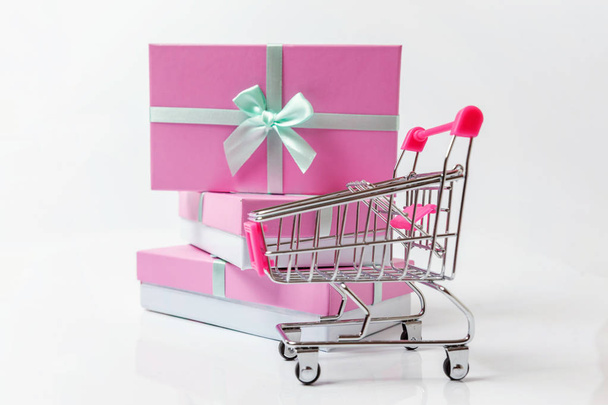 Niewielki supermarket spożywczy push wózek na zakupy Zabawka z różowe pudełko na białym tle. Sprzedam Kup mall rynku sklep pojęcie konsumenta. Miejsce - Zdjęcie, obraz