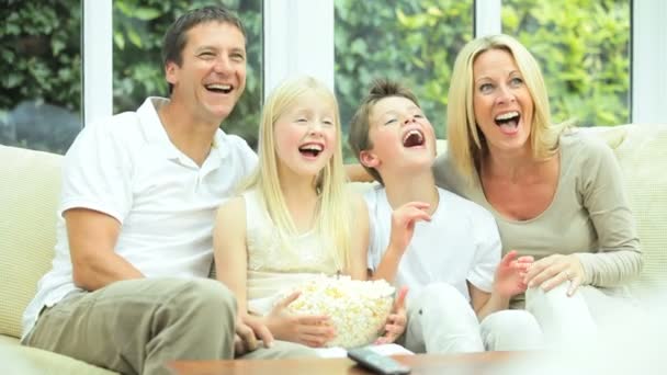 Família jovem assistindo filme em conjunto com pipoca
 - Filmagem, Vídeo