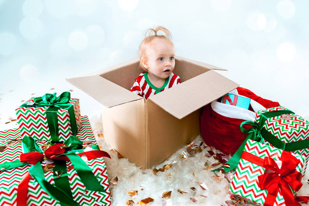 Cute baby girl 1 year old sitting at box over Christmas background. Holiday season. - Valokuva, kuva
