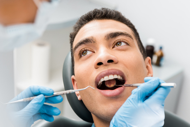  afro-americano com boca aberta durante check-up na clínica odontológica
  - Foto, Imagem