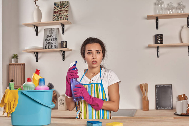 Красивая веселая брюнетка в перчатках чистит современную кухню
 - Фото, изображение