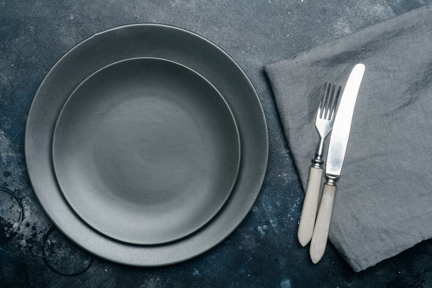 leerer grauer Teller (Keramik) auf dunkelgrauem Hintergrund mit Messer und Gabel, dekoriert mit einem Lavendelstrauß und einer Serviette. Grau minimalistisches Konzept. Kopierraum. - Foto, Bild