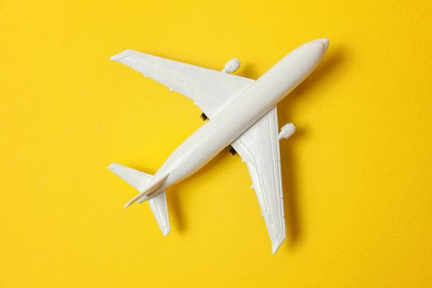 Gewoon plat lag ontwerp miniatuur speelgoed model vliegtuig op gele kleurrijke papier trendy achtergrond. Reizen per vliegtuig vakantie zomer weekend zee avontuur reis reis ticket tour concept - Foto, afbeelding