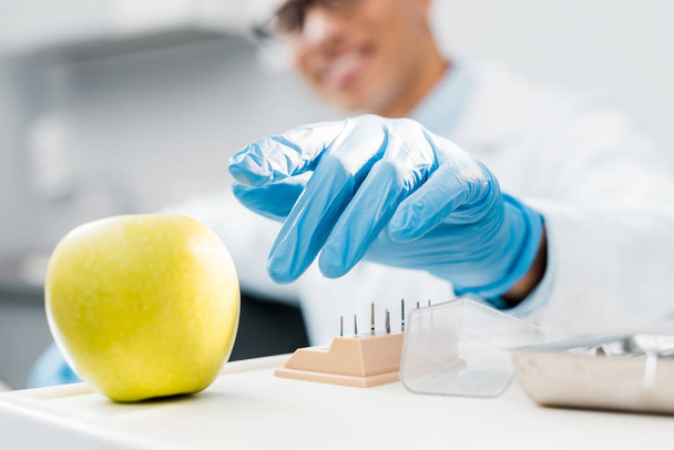 вибірковий фокус руки афроамериканського стоматолога в латексній рукавичці біля смачного яблука
  - Фото, зображення