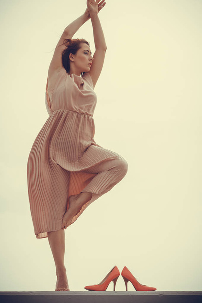 Hobby, idyllic aspects of femininity concept. Woman dancing on jetty without shoes wearing beautiful long light pink dress. - Foto, Imagem