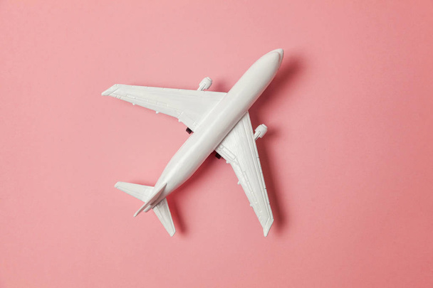 Simply flat lay design miniature toy model plane on pink pastel colorful paper trendy background. Travel by plane vacation summer weekend sea adventure trip journey ticket tour concept - Fotografie, Obrázek