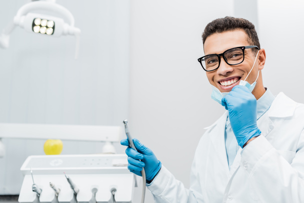 sonriente dentista afroamericano en gafas sosteniendo taladro
  - Foto, Imagen