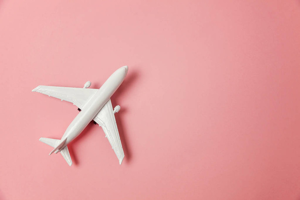 Simply flat lay design miniature toy model plane on pink pastel colorful paper trendy background. Travel by plane vacation summer weekend sea adventure trip journey ticket tour concept - Zdjęcie, obraz