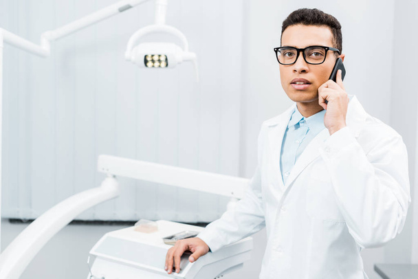 vakava afrikkalainen amerikkalainen hammaslääkäri lasit puhuvat älypuhelimella
  - Valokuva, kuva