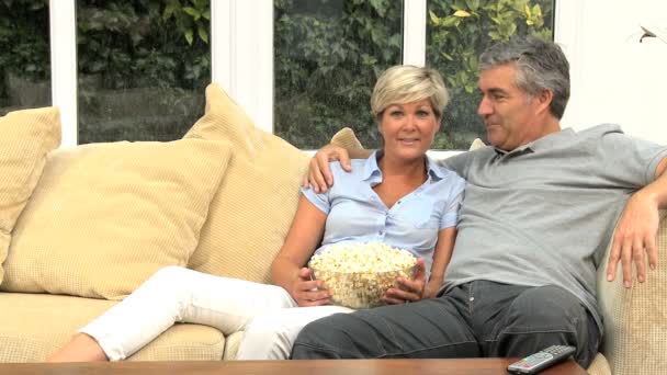ώριμο ζευγάρι τρώγοντας ποπ κορν μπροστά από την τηλεόραση - Πλάνα, βίντεο