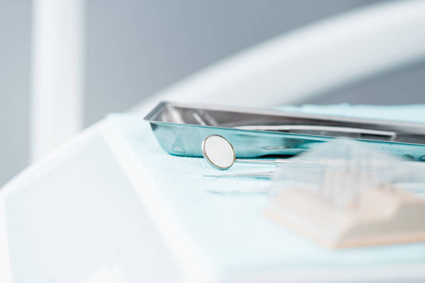 foco seletivo de espelho dental metálico perto de instrumentos na clínica
 - Foto, Imagem