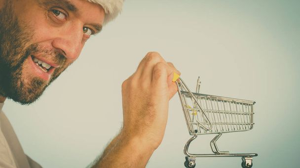 Man holding empty shopping basket cart, toned image. Seasonal sales, boxing day concept. - Foto, imagen