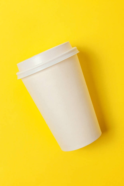 Απλά επίπεδη lay σχεδιασμό χαρτιού καφέ Κύπελλο σε κίτρινο φόντο πολύχρωμα μοντέρνα. Ποτό takeaway εμπορευματοκιβωτίων. Καλημέρα Ξυπνήστε ξύπνιοι έννοια. Πρότυπο ποτό κοροϊδεύω. Το top view αντίγραφο χώρου - Φωτογραφία, εικόνα