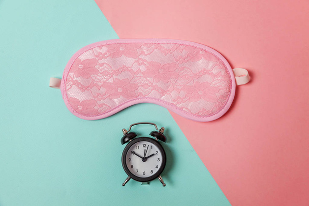 Sleeping eye mask, alarm clock isolated on blue pink pastel colorful trendy geometric background Do not disturb me, let me sleep. Rest, good night, siesta, insomnia, relaxation, tired, travel concept - Photo, image