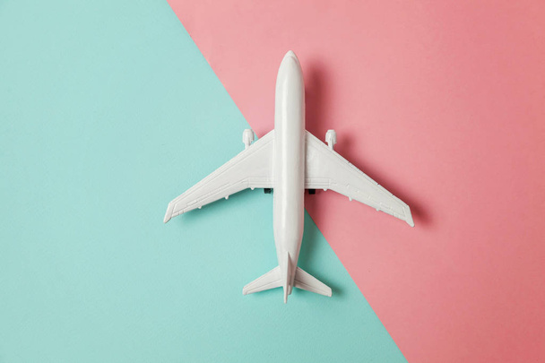 単に平らな青色とピンク色のパステル カラーのカラフルな紙のトレンディな幾何学的な背景にレイアウト デザイン ミニチュアおもちゃ模型飛行機。平面休暇夏の週末海冒険旅行コンセプトで旅行します。 - 写真・画像
