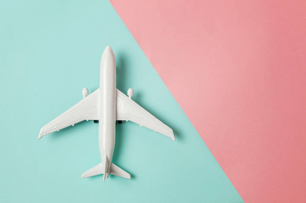 単に平らな青色とピンク色のパステル カラーのカラフルな紙のトレンディな幾何学的な背景にレイアウト デザイン ミニチュアおもちゃ模型飛行機。平面休暇夏の週末海冒険旅行コンセプトで旅行します。 - 写真・画像