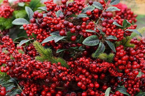 новорічний декор зі штучних червоних ягід і зеленого листя
 - Фото, зображення