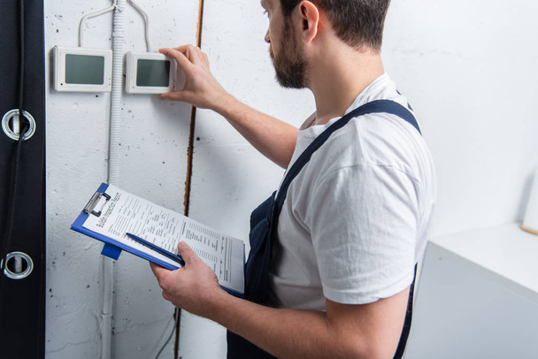 adult bearded electrician with clipboard checking electrical panel - Photo, Image