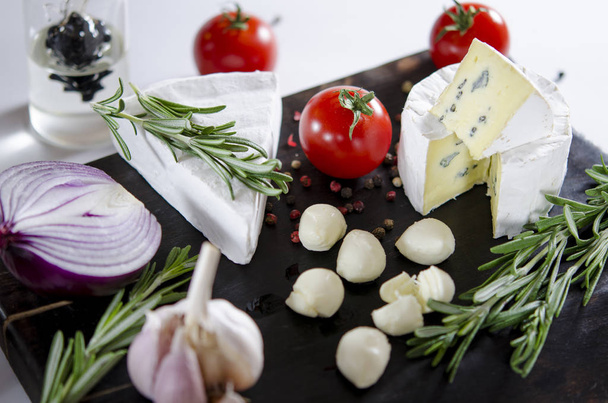 Tasting cheese dish with tomatos on old black dask. Food for wine and romantic, cheese delicatessen. Menu design horizontal. Top view. - Photo, Image