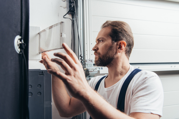 concentrated male bearded handyman checking electrical box  - Φωτογραφία, εικόνα