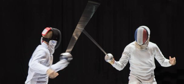 プロのスポーツ アリーナで戦う 2 人のフェンシングの選手  - 写真・画像