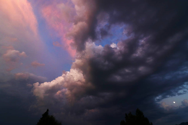 Een zonsondergang met gekleurde en donkere wolken. Sundown met onweerslucht - Foto, afbeelding