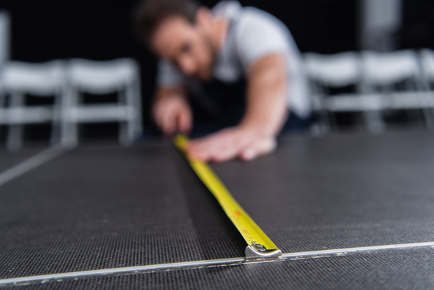 enfoque selectivo del artesano masculino haciendo mediciones del piso mediante cinta métrica
 - Foto, Imagen