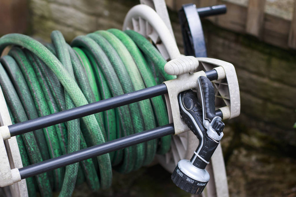 Old garden hose and spray nozzle on a reel. - Photo, Image