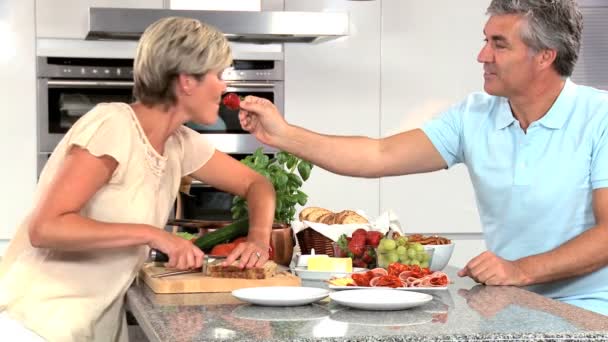 Pareja de mediana edad preparando el almuerzo en la cocina
 - Metraje, vídeo