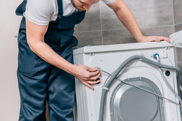 partial view of male handyman repairing washing machine in bathroom - Foto, Bild