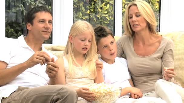 Ελκυστική οικογένεια απολαμβάνοντας τηλεόραση & ποπ κορν - Πλάνα, βίντεο