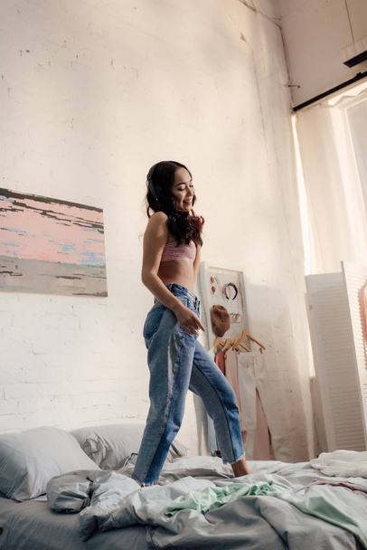 beautiful happy asian girl standing on bed and looking down - Fotoğraf, Görsel