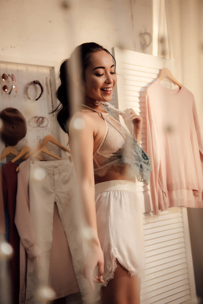 beautiful smiling young woman choosing what to wear in wardrobe - Foto, Imagen